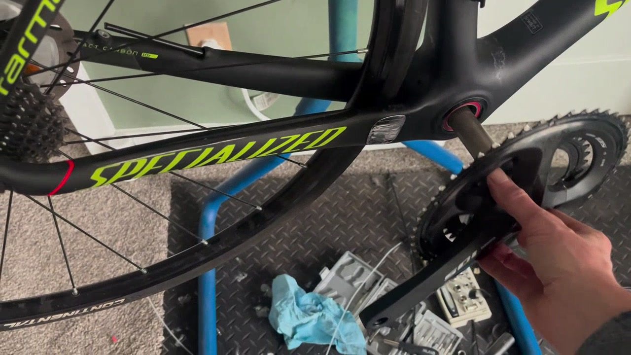 A hand on the chainring of a Specialized road bike.