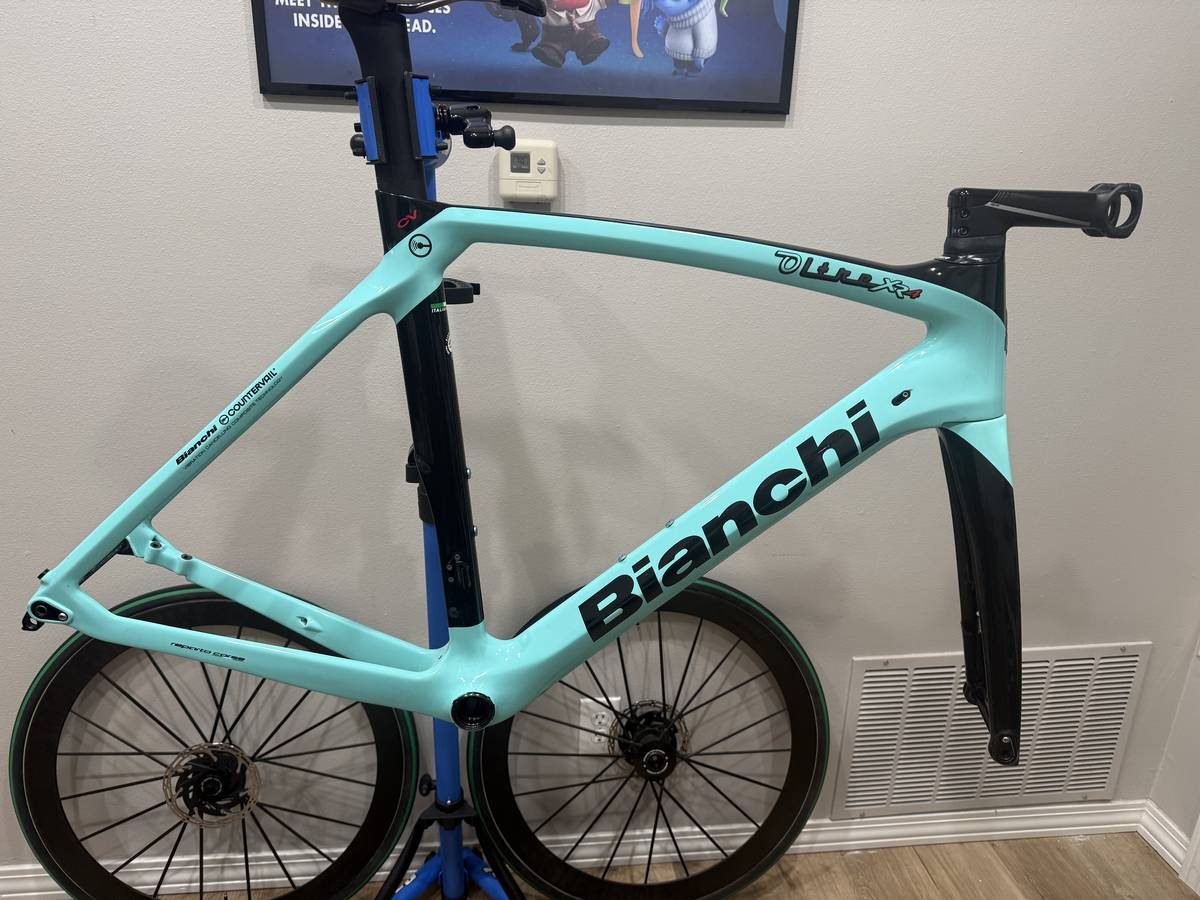 Celeste and black Bianchi Oltre XR4 frame and fork with the black Vision cockpit fitted, on a blue work stand with wheels in, from the seller's Craigslist listing.