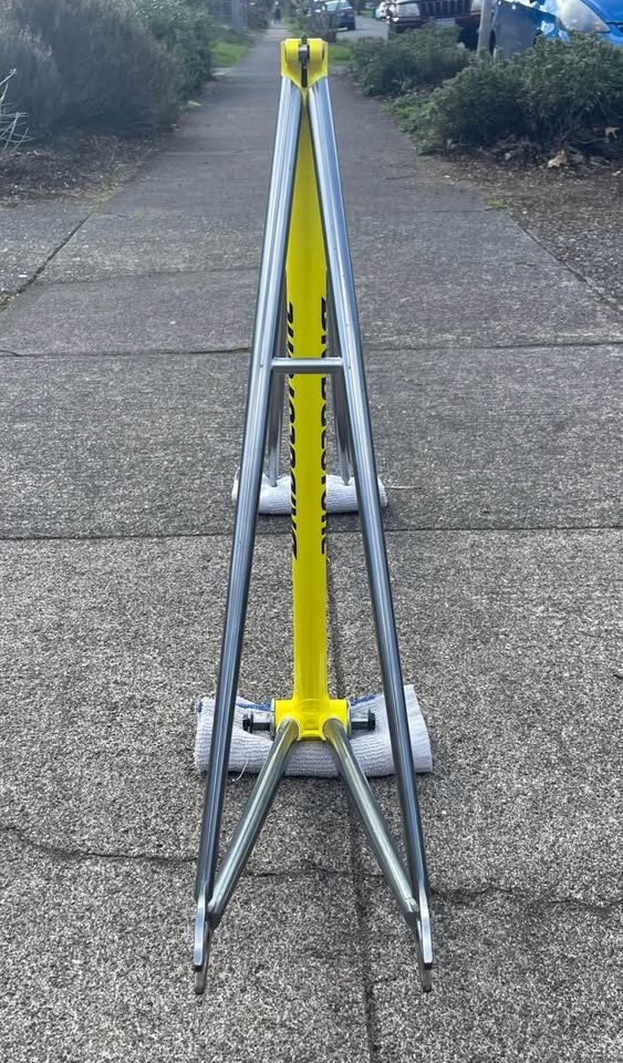 Yellow Bridgestone track frame with a polished silver rear triangle propped on a pavement beside its matching silver fork, from the seller's Marketplace listing. Photo 3 of 5.