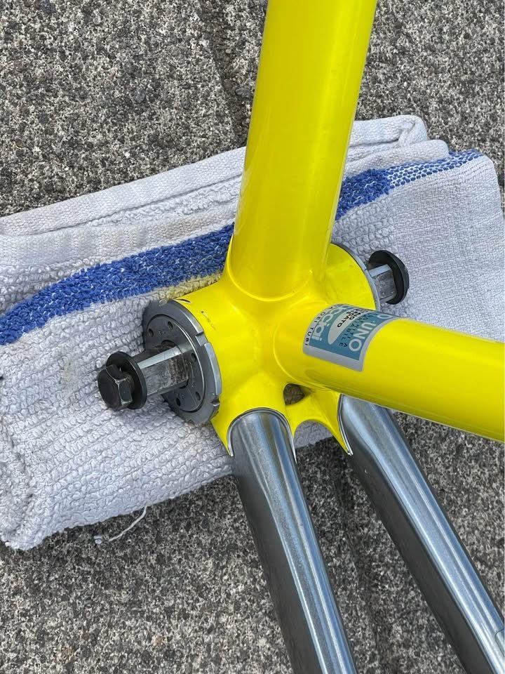 Yellow Bridgestone track frame with a polished silver rear triangle propped on a pavement beside its matching silver fork, from the seller's Marketplace listing. Photo 5 of 5.