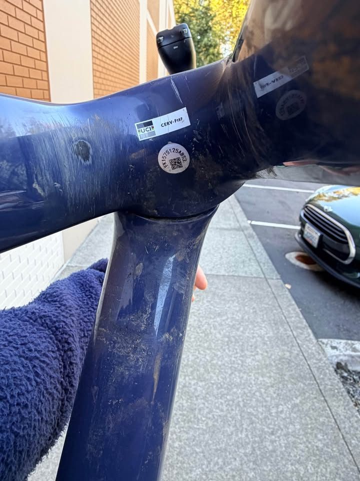 Dark blue Cervélo Áspero frame and fork with a stem and seatpost fitted and purple axles, leaning against a white brick wall, from the seller's Marketplace listing. Photo 9 of 9.