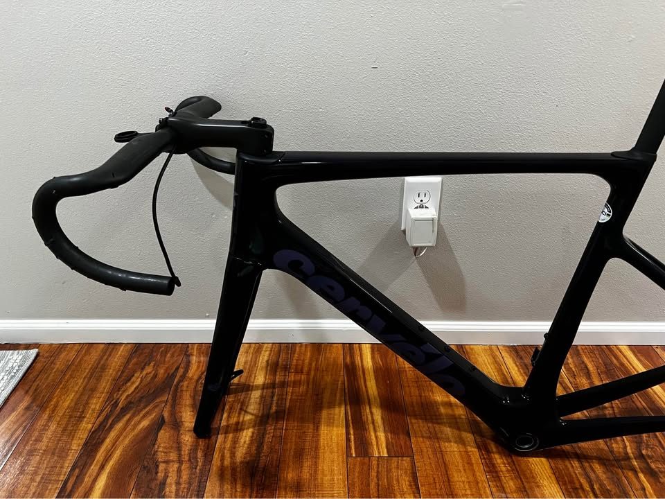 Black Cervélo Caledonia-5 frameset with the bar and stem fitted, leaning against a wall on a wood floor, from the seller's Marketplace listing. Photo 6 of 7.