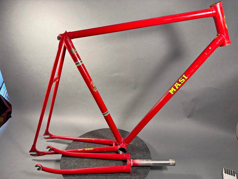 Red lugged steel Masi track frame and matching fork on a grey studio backdrop, MASI in yellow on the down tube and Italian tricolour bands on the seat tube, from the seller's Marketplace listing.