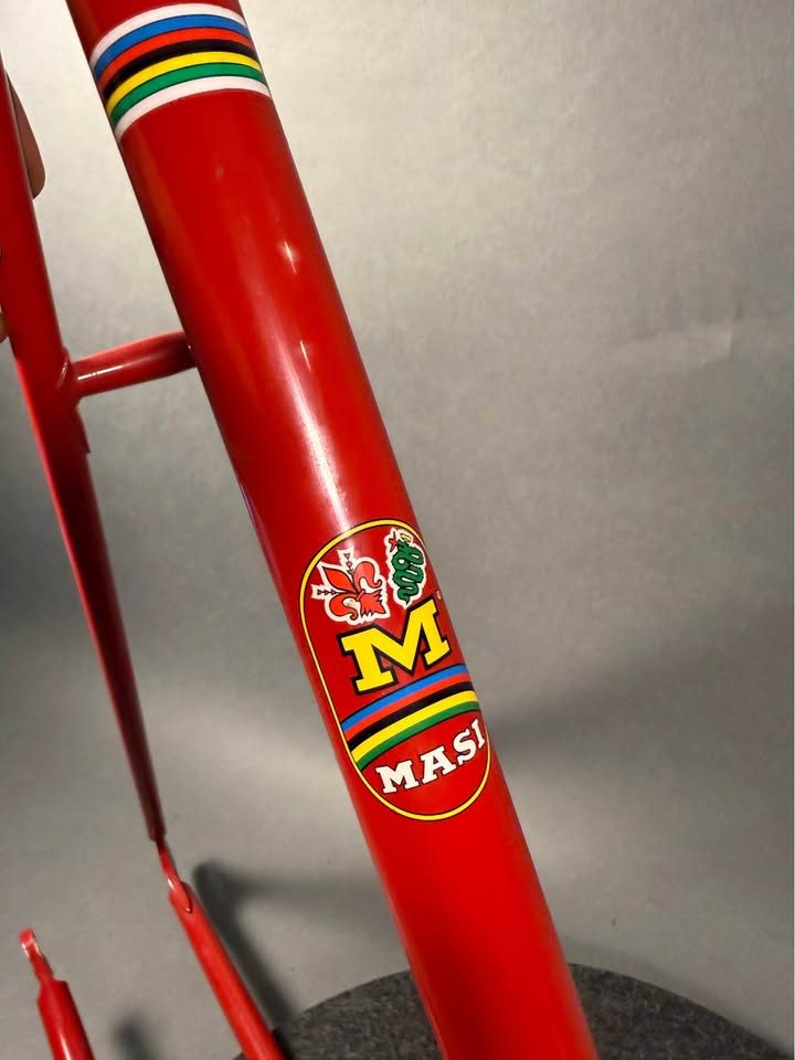 Red lugged steel Masi track frame and matching fork on a grey studio backdrop, MASI in yellow on the down tube and Italian tricolour bands on the seat tube, from the seller's Marketplace listing. Photo 4 of 10.