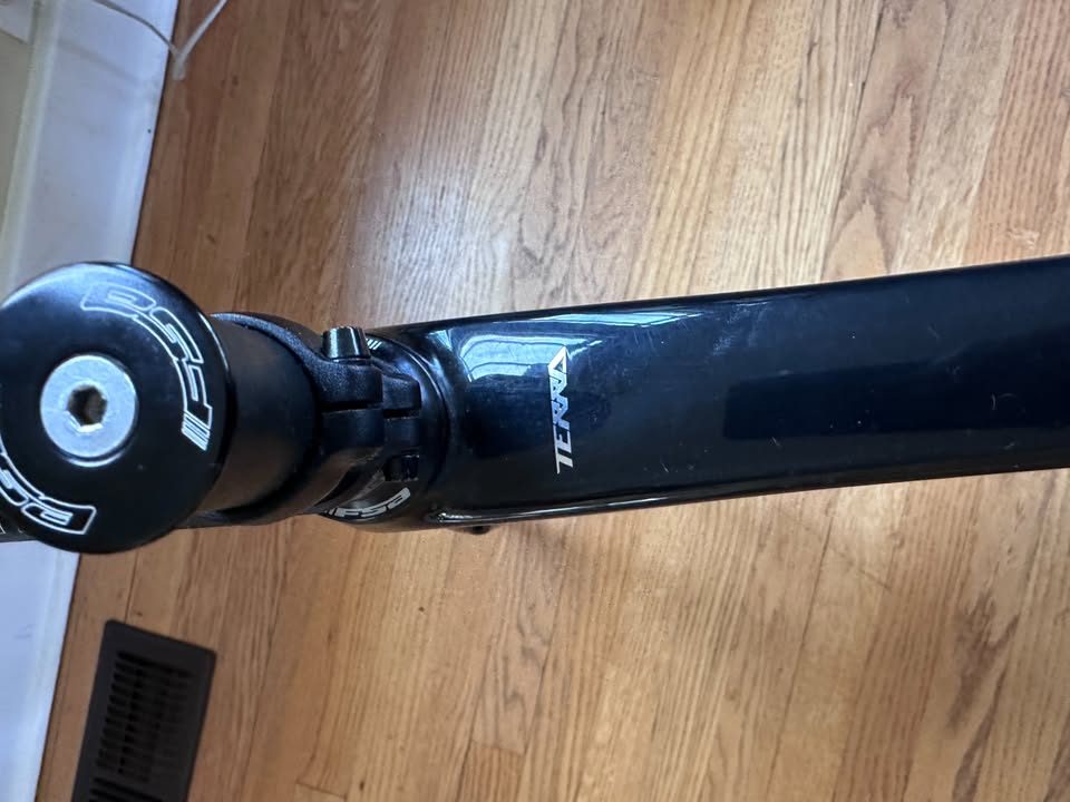 Black Orbea Terra carbon frame and fork with a Rotor crankset fitted and a handlebar and stem on the fork, standing on a wood floor, from the seller's Marketplace listing. Photo 7 of 10.