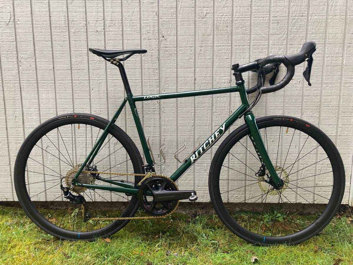 Dark green Ritchey Logic steel road bike built with a Shimano Ultegra crank and black wheels, leaning on a white wall, from the seller's Craigslist listing.