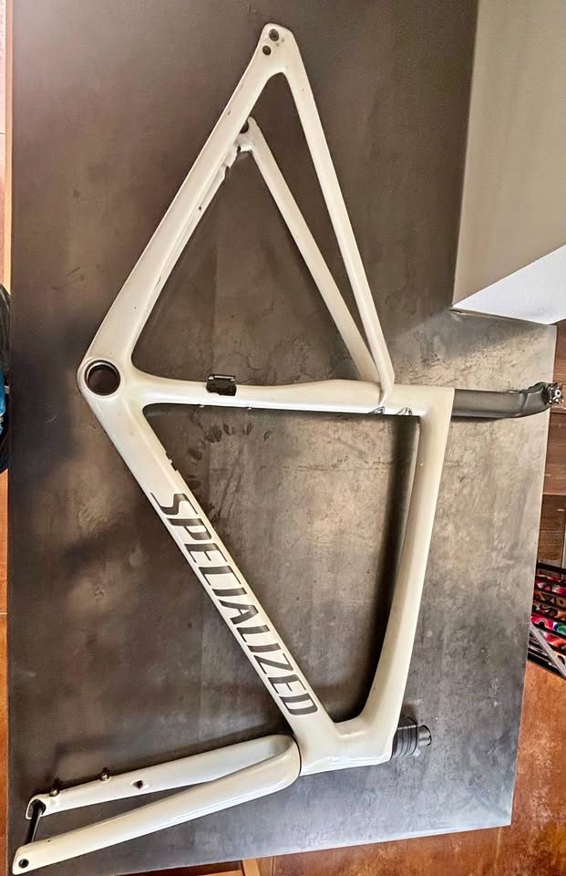 Off-white Specialized Tarmac SL7 frame laid on a dark table with its fork and carbon seatpost alongside, from the seller's Marketplace listing.